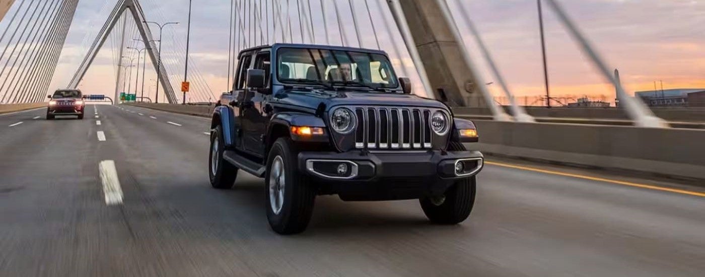 Black 2023 Jeep Wrangler Unlimited driving over a bridge