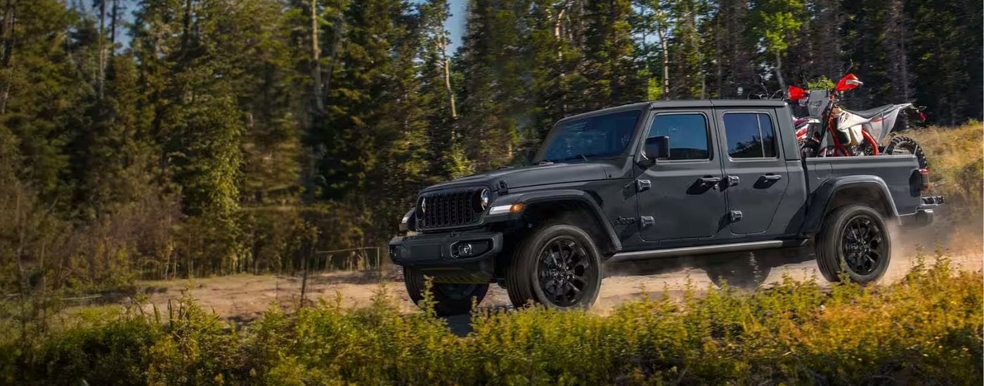 Black 2025 Jeep Gladiator Nighthawk hauling a dirtbike