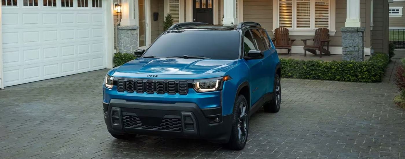 Blue 2026 Jeep Cherokee parked in a driveway.