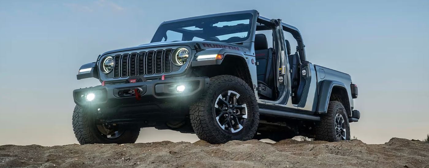 Grey 2026 Jeep Gladiator Rubicon X with no doors or roof on a rocky hill.