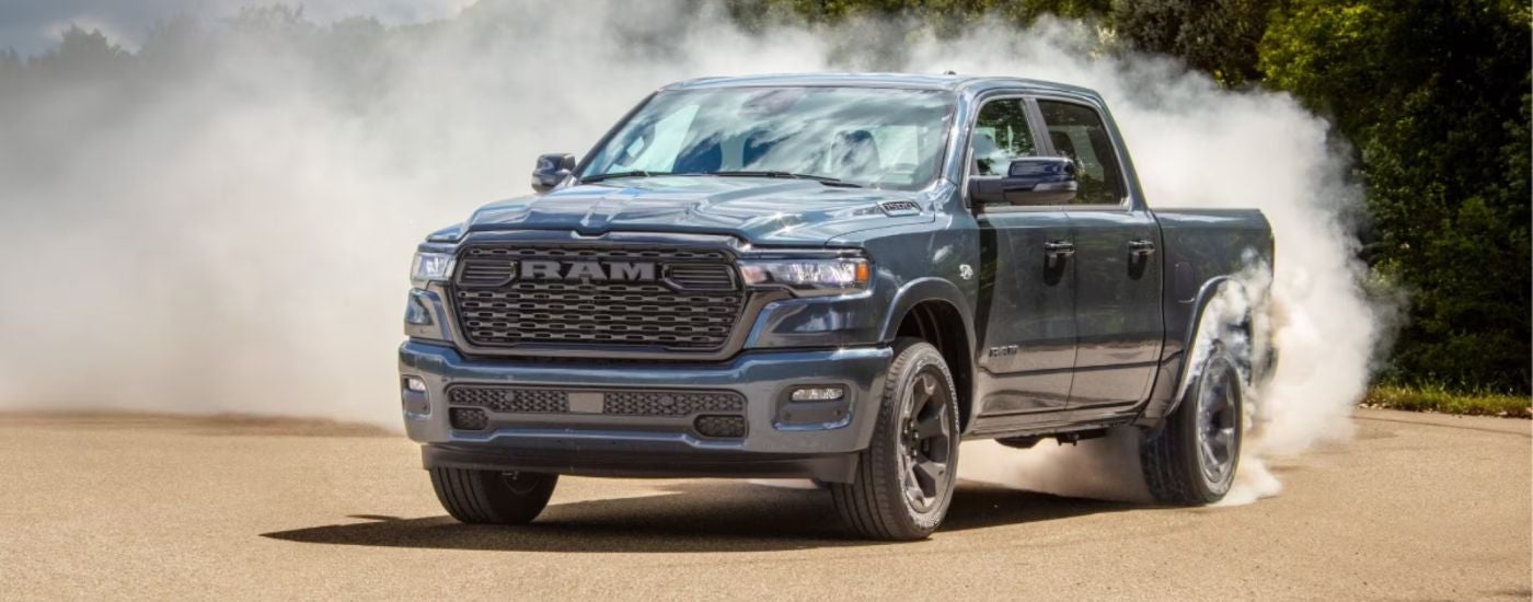 Grey 2026 Ram 1500 sending up a dust cloud on a dirt path.