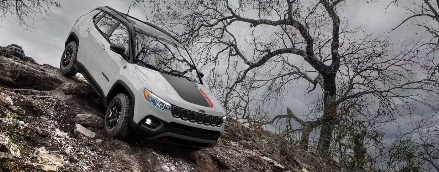 White 2026 Jeep Compass Trailhawk driving down rocks.