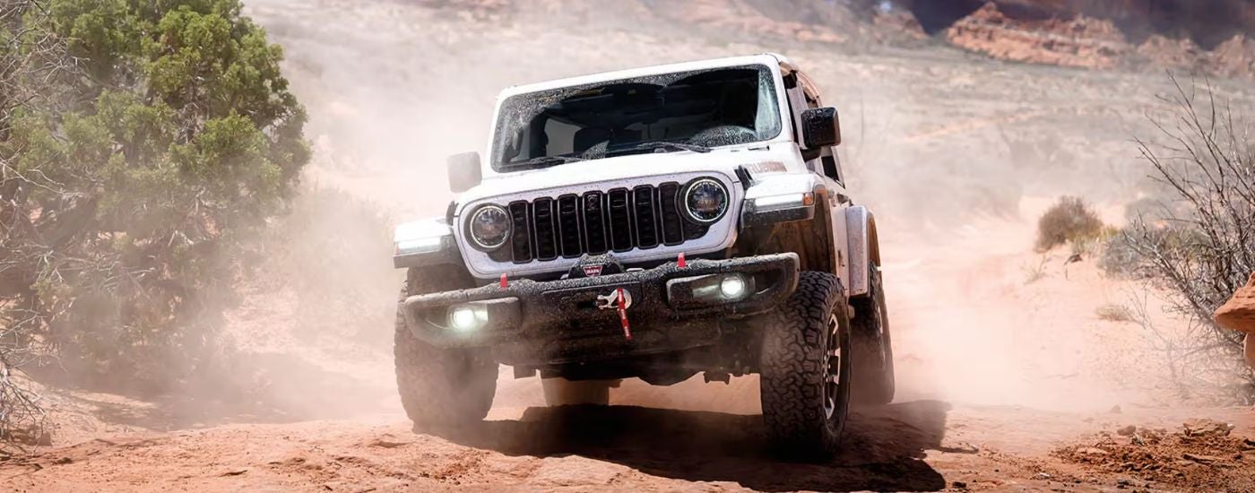 White 2026 Jeep Wrangler driving off-road in the desert.