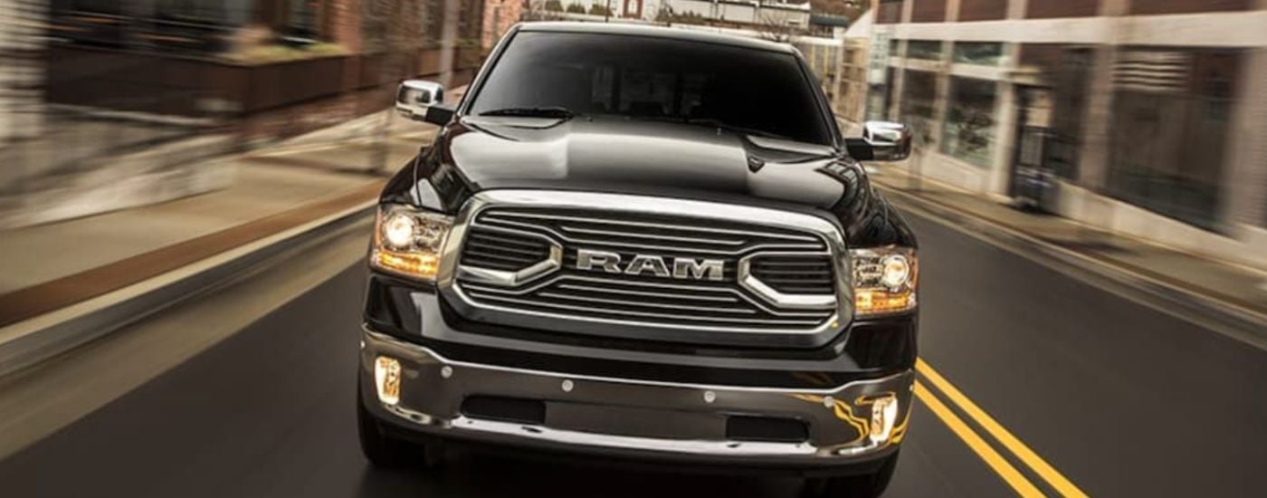 A black 2018 Ram 1500 is shown from the front driving.