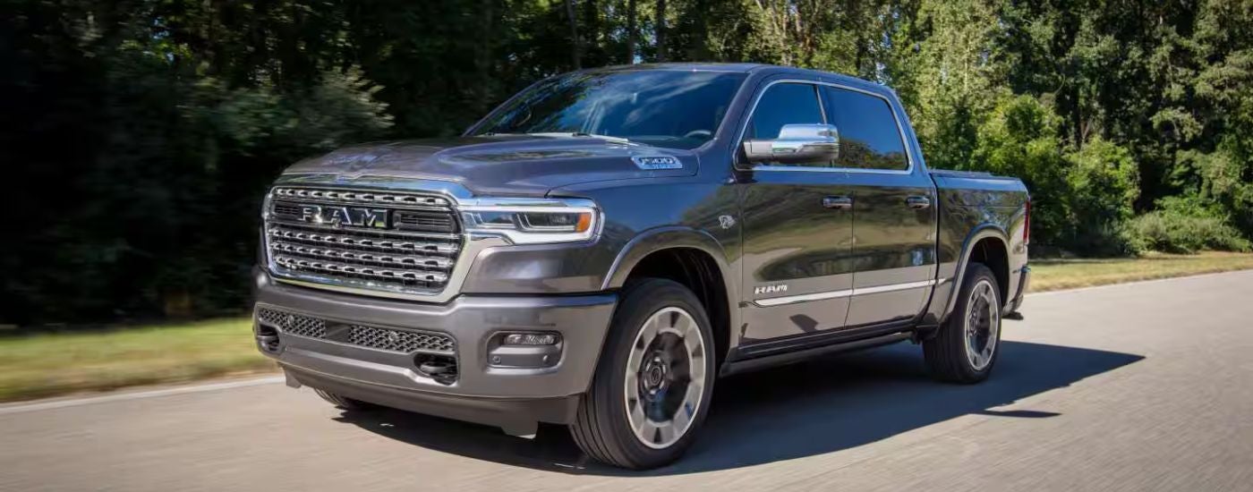 A gray 2027 Ram 1500 Limited driving a country road.